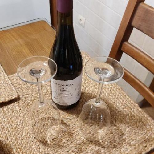 Mesa preparada con botella de vino y dos copas en ambiente rural
